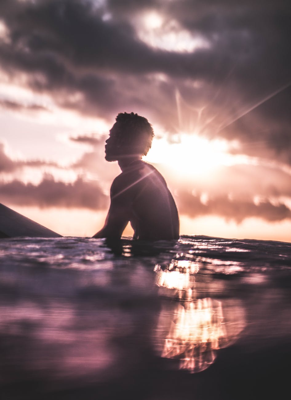 unrecognizable black man relaxing in sea water at sundown